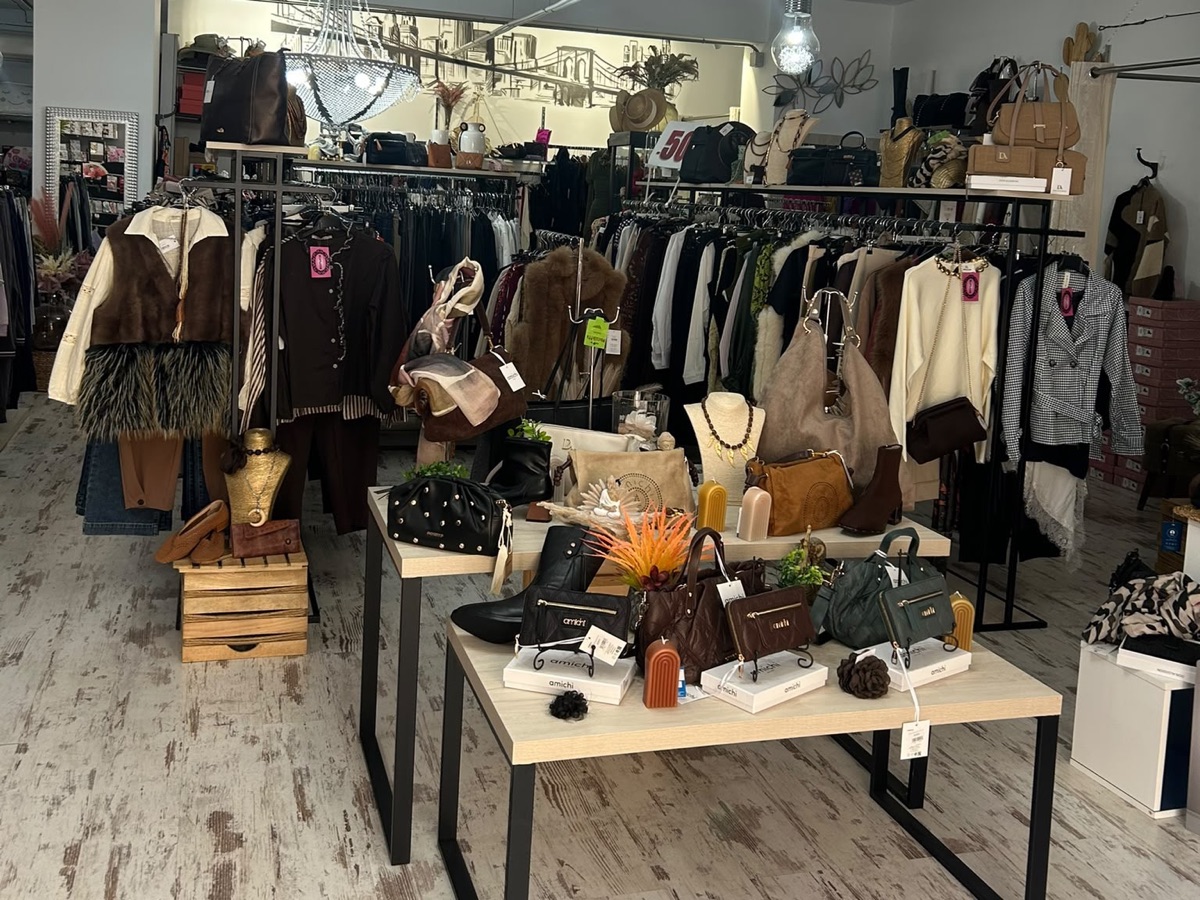 Interior de la tienda Inma Calero en Escacena del Campo, con percheros de ropa y mesas de bolsos y calzado